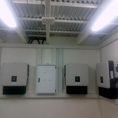 Row of FoxESS three-phase inverters installed by Crown Technologies in a commercial plant room